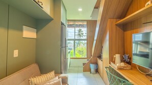 Una cocina moderna con encimera de madera, horno integrado y ventana con vistas a palmeras.