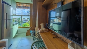 Una cocina moderna con un televisor de pantalla plana grande, armarios de madera y vistas de la ciudad a través de un ventanal amplio.