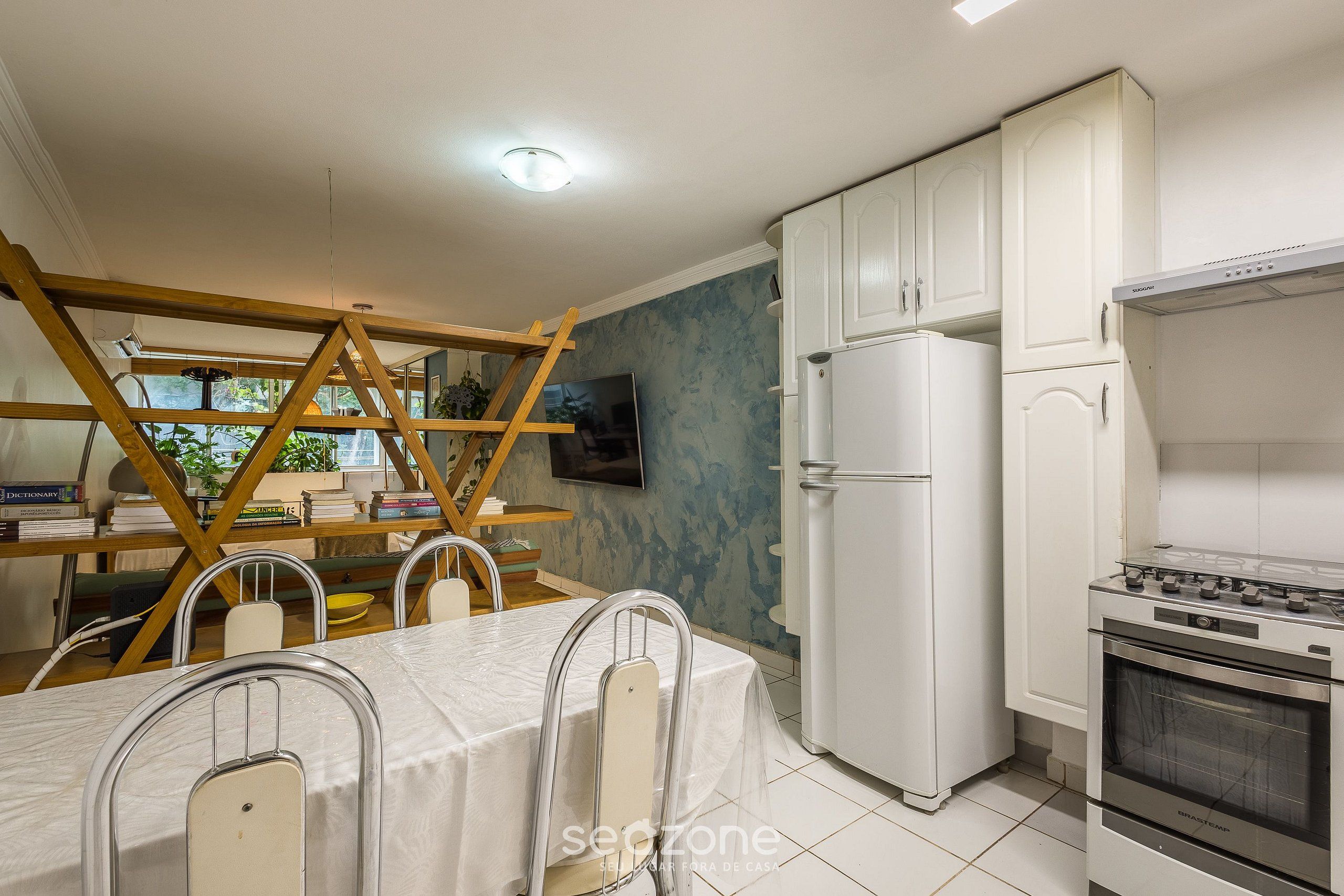 A kitchen with white cabinets, a built-in oven, and a dining area with a table and chairs.