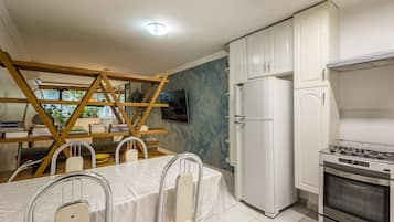 A kitchen with white cabinets, a built-in oven, and a dining area with a table and chairs.