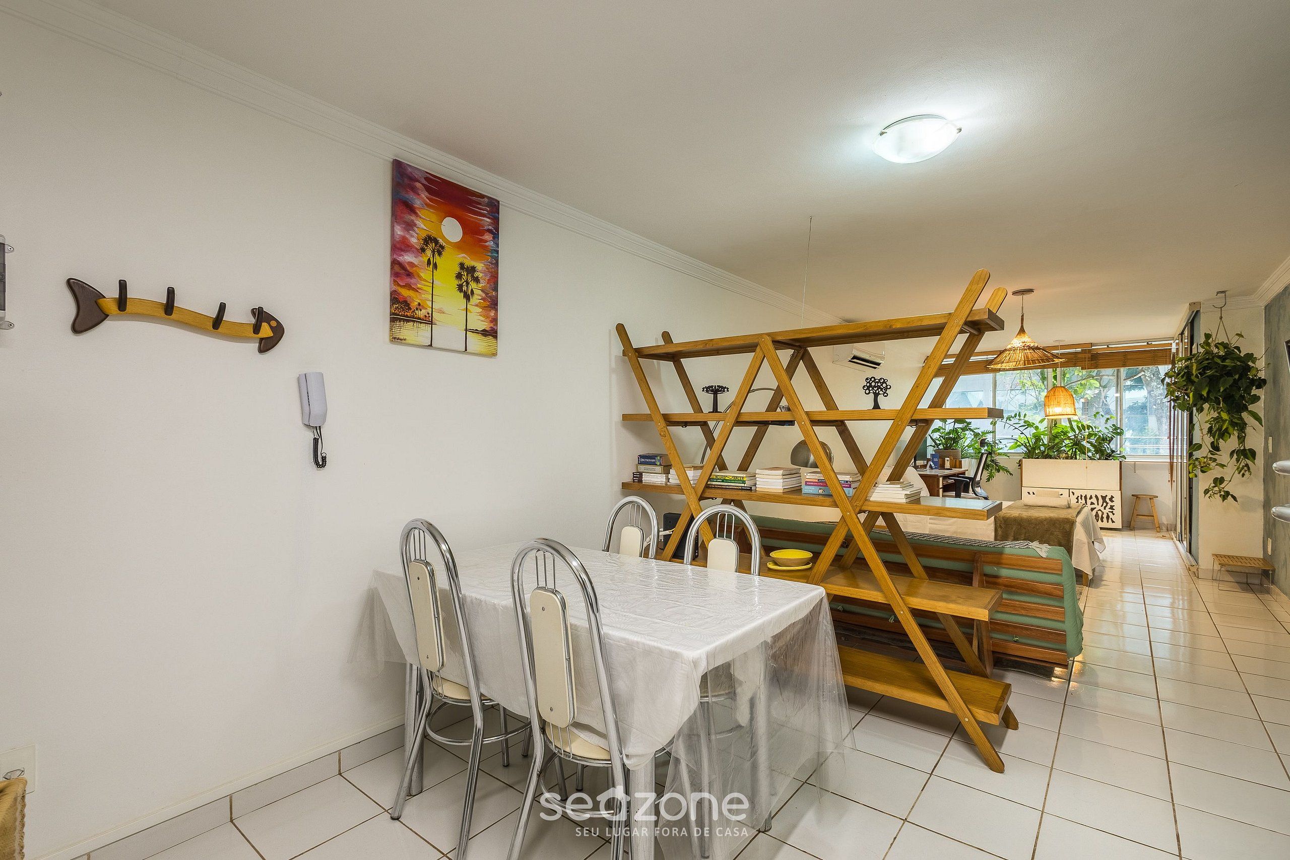 A dining area with a table and chairs, a ladder structure, and a painting on the wall.