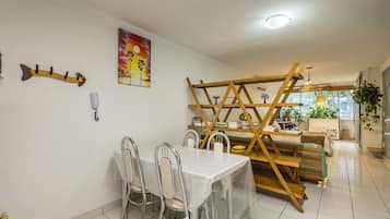 A dining area with a table and chairs, a ladder structure, and a painting on the wall.