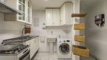 A kitchen with white cabinets, a sink, a stove, and a washing machine.