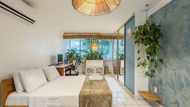 Ett modernt hotellrum med en säng, ett skrivbord och ett stort fönster.