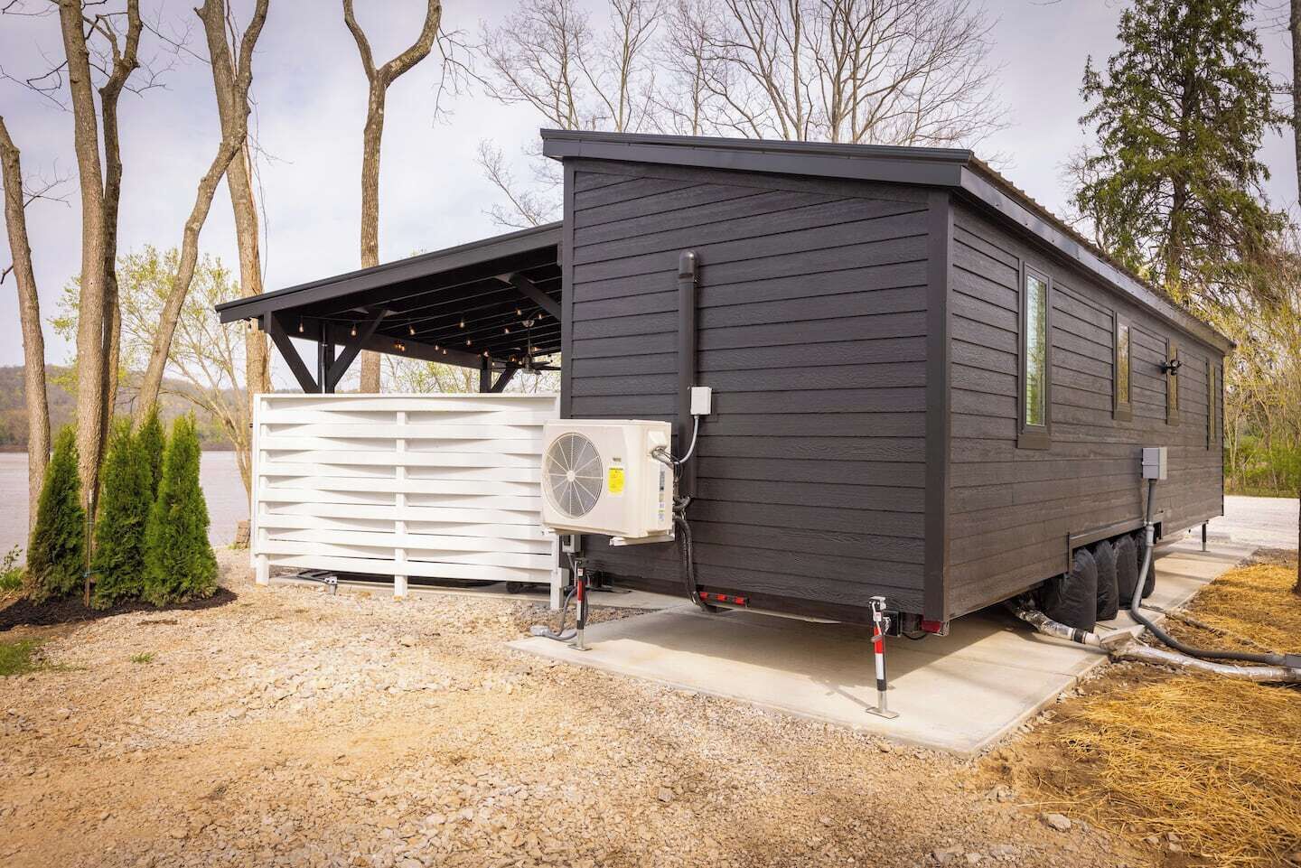 A mobile home with a covered porch, an air conditioning unit, and a water heater.