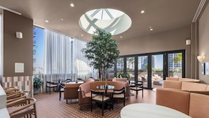 Un área de estar moderna con disposiciones de asientos, una mesa central y una planta grande en maceta.