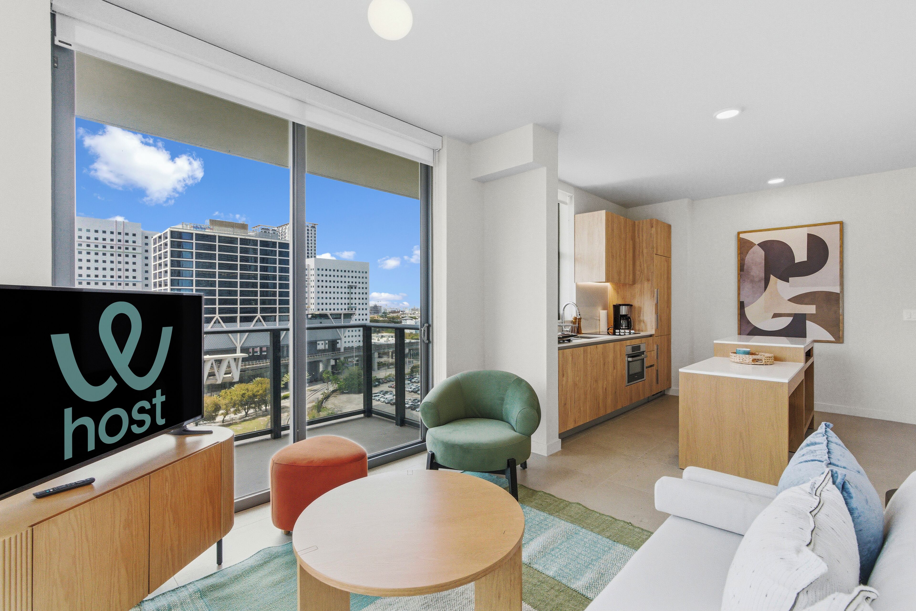 A modern apartment with a large window, a kitchen, a living area with a sofa and a TV, and a dining table.