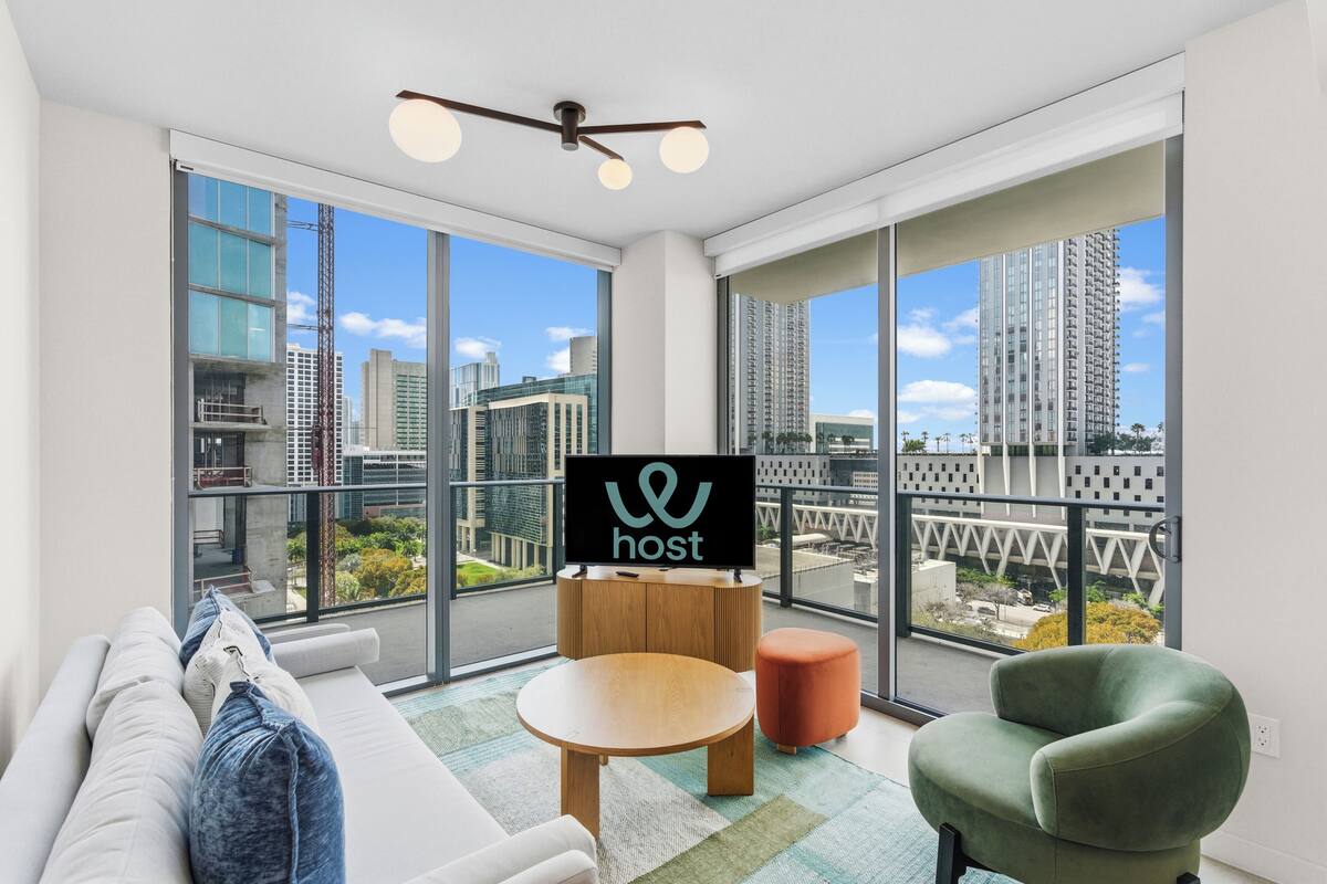 A modern living room with a sofa, a green armchair, a wooden side table, and a television displaying the word "host".