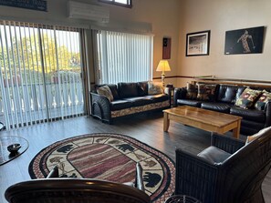 Ein geräumiges Wohnzimmer mit großem Fenster, Kamin und Blick ins Freie.