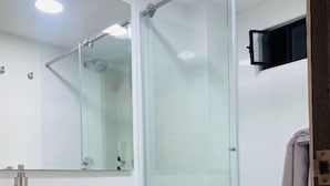 A modern bathroom with a glass shower enclosure, a white toilet, and a wooden vanity. - Hotel 86 Suites (Bogotá)