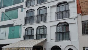 A multi-story building with a white facade, multiple balconies, and a gated entrance. - Hotel 86 Suites (Bogotá)