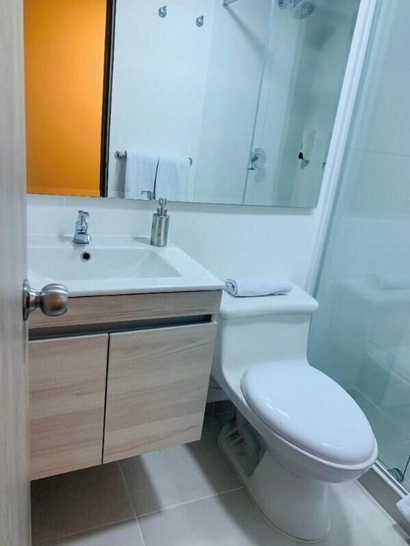 A bathroom with a white sink, a toilet, and a glass shower enclosure. - Hotel 86 Suites (Bogotá)