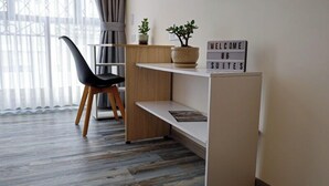 A modern, minimalistic room with a wooden desk, a black chair, and a welcome sign. - Hotel 86 Suites (Bogotá)