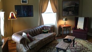 Un salón con sofá de cuero, una mesita, un sillón rojo y una alfombra estampada.