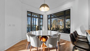 A dining area with a round table, six chairs, and large windows offering views of the outdoors. - Lion Manor by Avantstay Spacious Lake Norman Home Hot Tub + Tennis Court + Firepit + Deck (Denver)