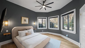 A bedroom with a bed, a ceiling fan, and three windows. - Lion Manor by Avantstay Spacious Lake Norman Home Hot Tub + Tennis Court + Firepit + Deck (Denver)