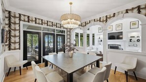A dining area with a large table, chairs, a chandelier, and a view of the outdoors. - Lion Manor by Avantstay Spacious Lake Norman Home Hot Tub + Tennis Court + Firepit + Deck (Denver)