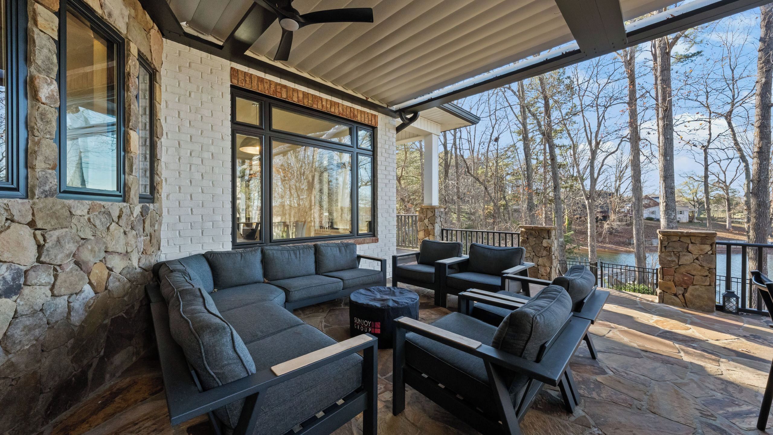 A covered patio with stone walls, a sectional sofa, and a dining area.
