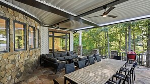 An outdoor patio with stone walls, a wooden table, and a red grill. - Lion Manor by Avantstay Spacious Lake Norman Home Hot Tub + Tennis Court + Firepit + Deck (Denver)