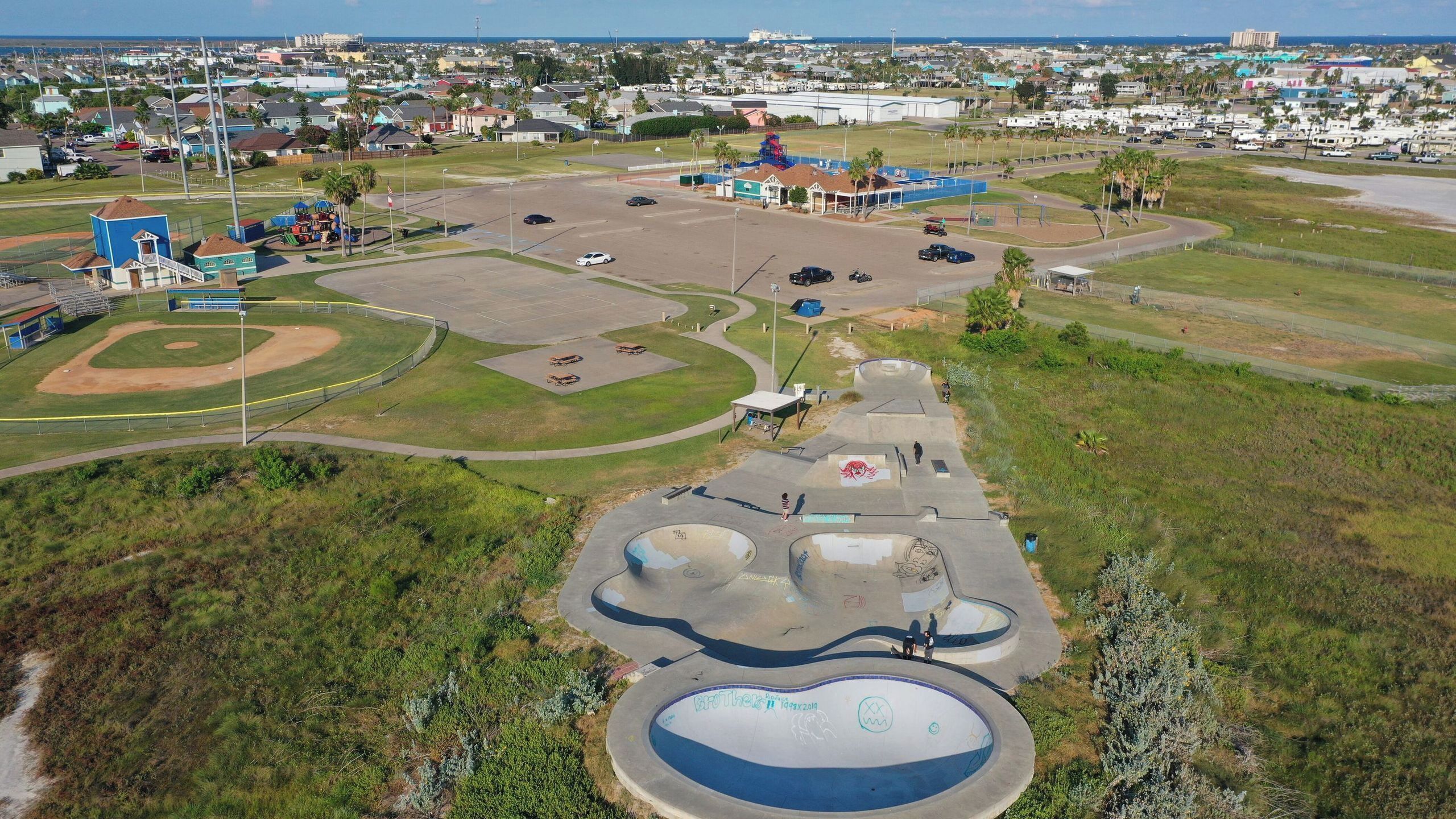 An aerial view of a park with a baseball field, skate park, and playground.