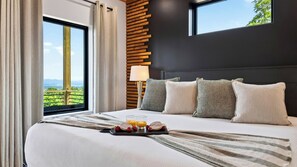 Ein Hotelzimmer mit einem großen Bett, Blick ins Grüne und einem Holzkopfende.