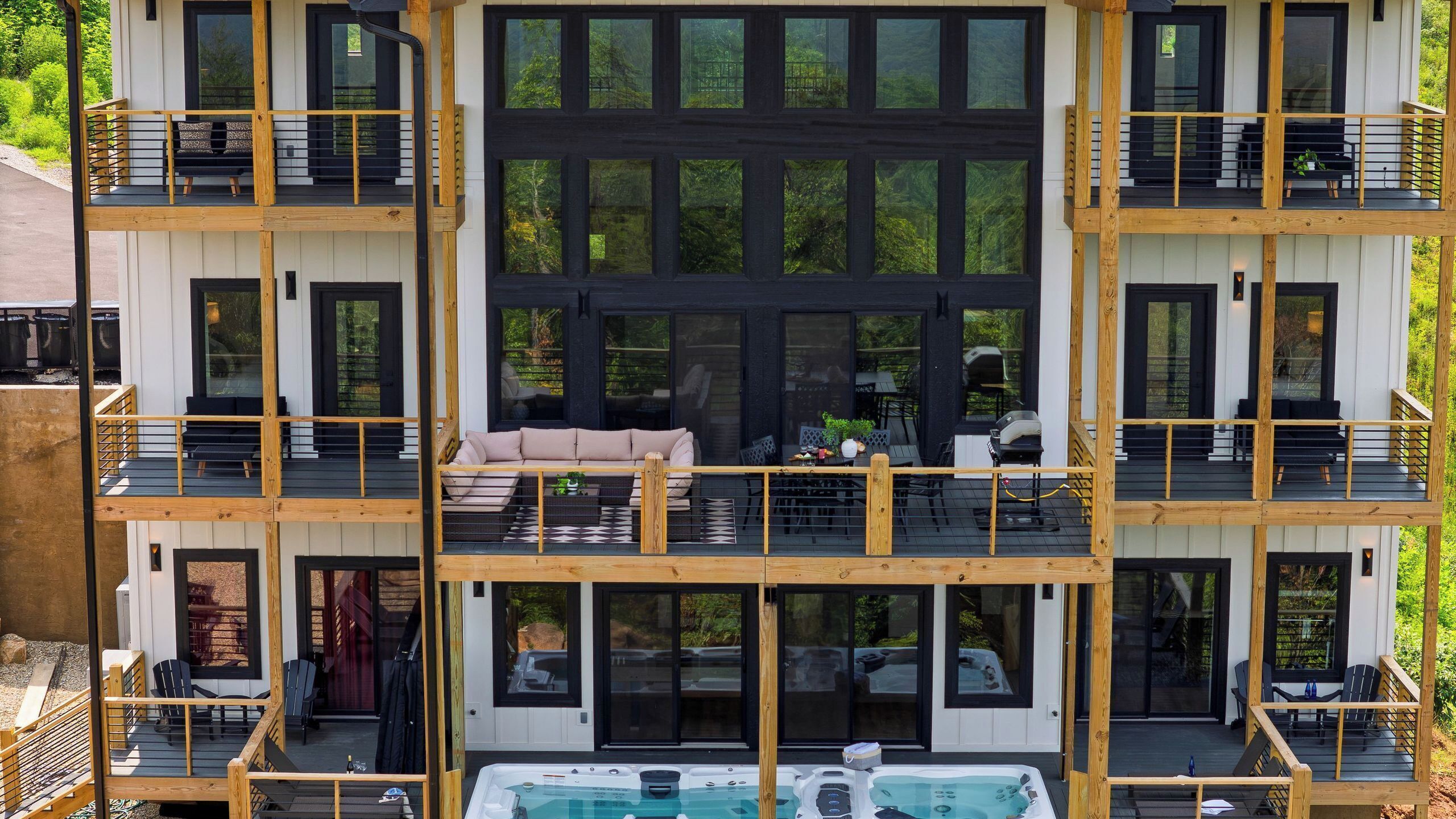A multi-level residential building with balconies, outdoor seating, and a swimming pool.
