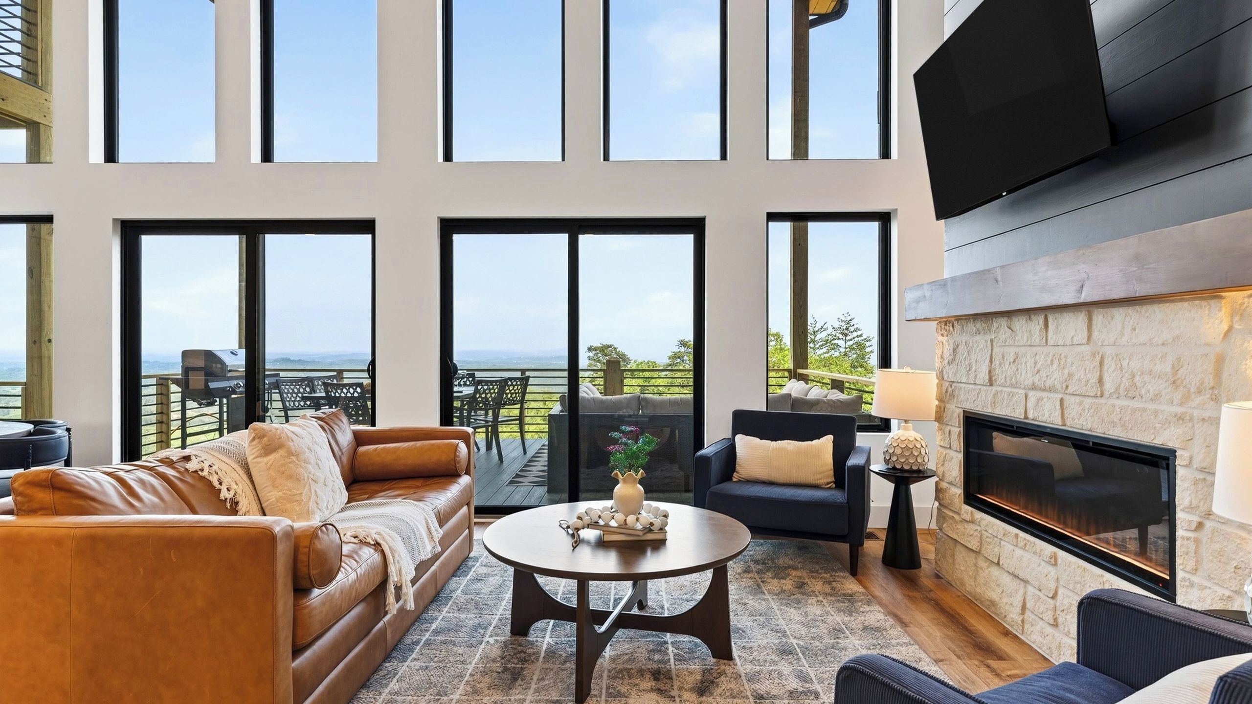 A spacious living room with a fireplace, large windows, and a view of the outdoors.