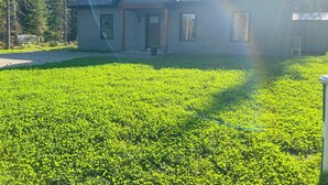 A house with a sloped roof, a front porch, and a well-maintained lawn. - St-Alexis en escapade nature et spa. Accès aux pistes de motoneiges a 3 minutes. (Saint-Alexis-des-Monts)