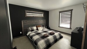 A bedroom with a bed, a window with blinds, a ceiling light, and a small desk with a lamp. - St-Alexis en escapade nature et spa. Accès aux pistes de motoneiges a 3 minutes. (Saint-Alexis-des-Monts)