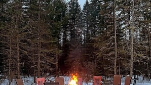 A snow-covered outdoor seating area with a fire pit surrounded by metal chairs. - St-Alexis en escapade nature et spa. Accès aux pistes de motoneiges a 3 minutes. (Saint-Alexis-des-Monts)