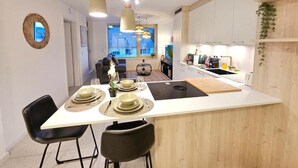 A modern kitchen with a central island, pendant lighting, and a view to the living area. - New 2BR Flat in Limpertsberg City center (Luxembourg City)