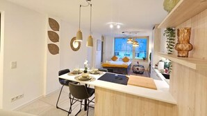 A modern kitchen with a central island, pendant lighting, and a view into the living area. - New 2BR Flat in Limpertsberg City center (Luxembourg City)