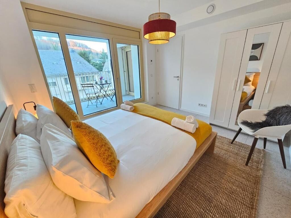 Un dormitorio con una cama grande, vistas al balcón exterior y una silla.
