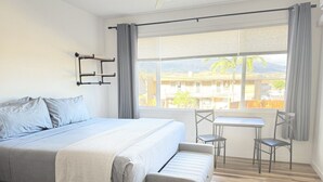 A bedroom with a bed, a small table, two chairs, and a window with curtains.