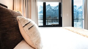 A hotel room with a bed, a window with a mountain view, and a balcony. - The Aspen Hydeaway at Ascent (Canmore)