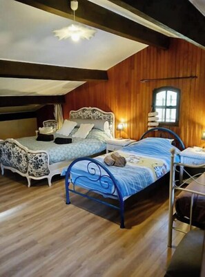 Un dormitorio con dos camas, paredes de madera, techo inclinado y una ventana.