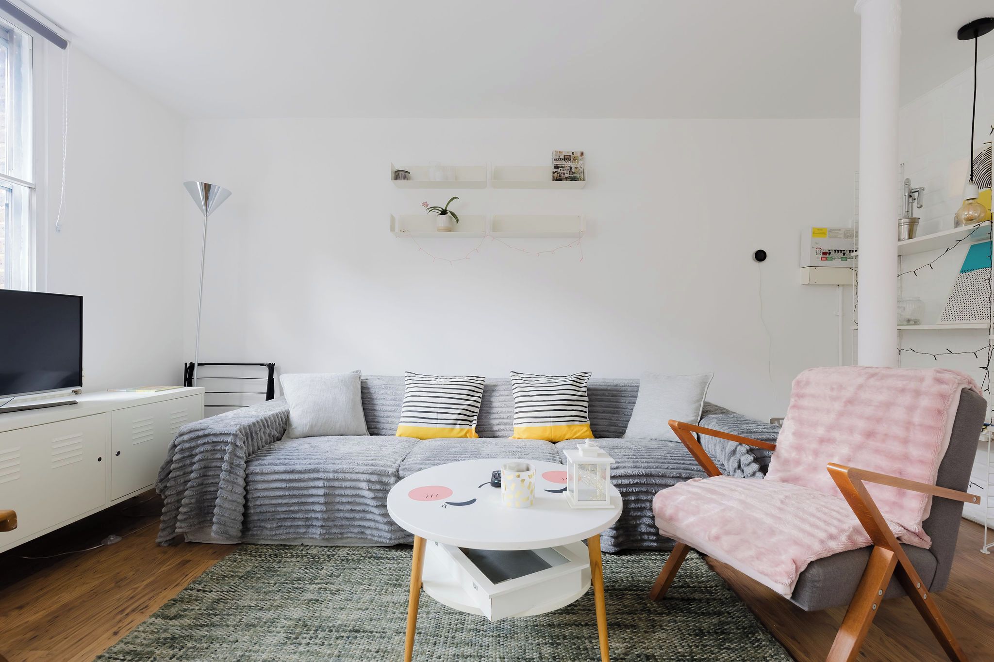 A modern living room with a sofa, armchair, and a small table with decorative items.