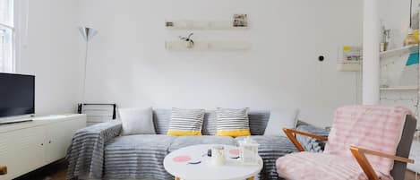 A modern living room with a sofa, armchair, and a small table with decorative items.
