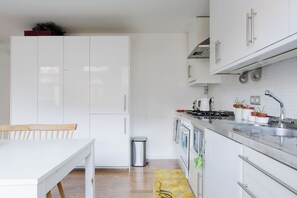 A modern kitchen with white cabinets, a stainless steel sink, and a gas stove. - Brilliantly Located 2BDR Flat in Barbican (Greater London)