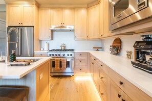 Una cocina moderna con armarios de madera, electrodomésticos de acero inoxidable y una isla central.