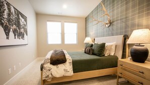 A bedroom with a bed, bedside lamps, a nightstand, a wall-mounted deer antler, and a framed picture. - 4BR Deer Valley East | Hot Tub | Shuttle + Views (Wasatch County)
