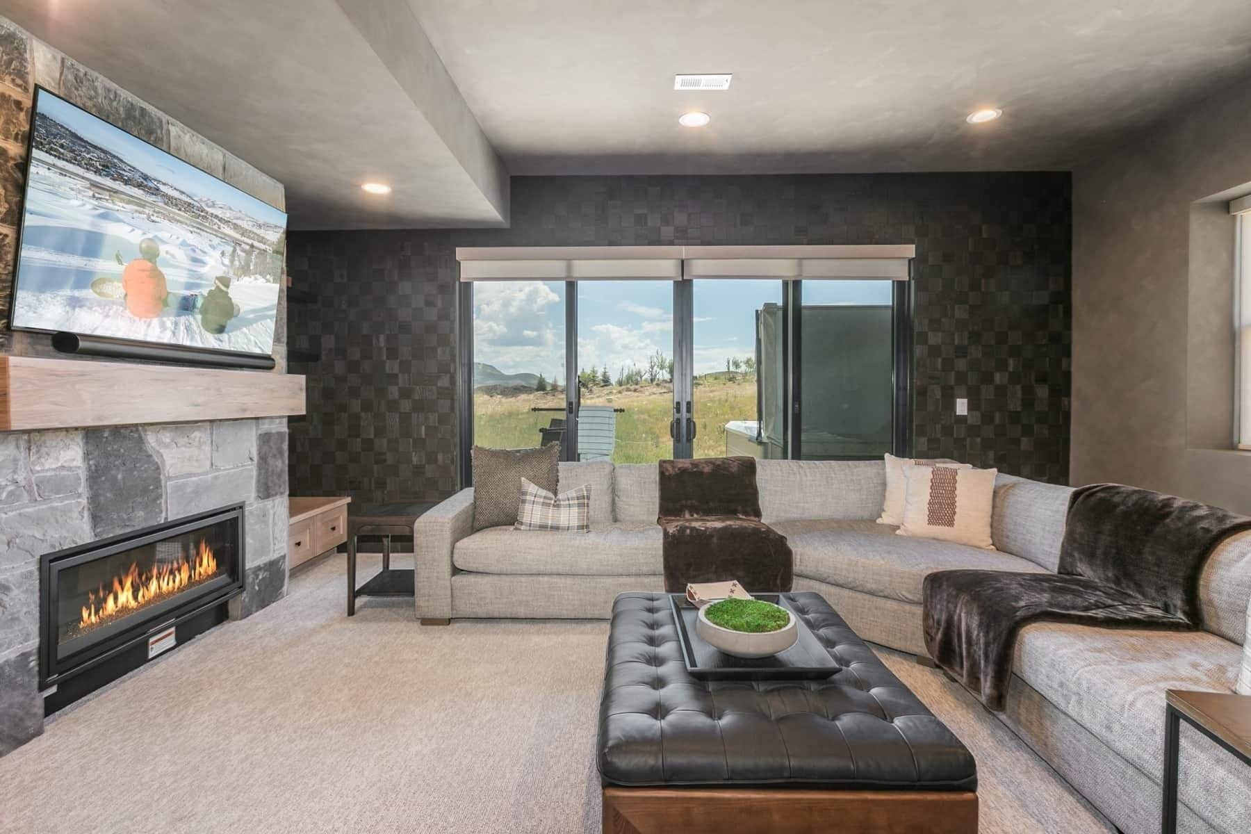 A modern living room with a fireplace, a large window, and a view of the outdoors.