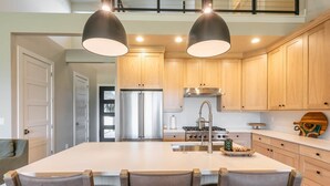 A modern kitchen with a central island, stainless steel appliances, and pendant lighting. - 4BR Deer Valley East | Hot Tub | Shuttle + Views (Wasatch County)