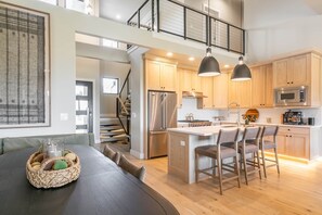 Eine moderne Küche mit Holzschränken, einem Edelstahlkühlschrank und einer zentralen Kochinsel mit Barhocker.