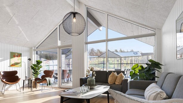 Ein geräumiges Wohnzimmer mit großem Fenster, einem runden Tisch und modernen Möbeln.