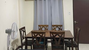 Ein Essbereich mit Tisch, Stühlen, Deckenventilator und einer Tür.