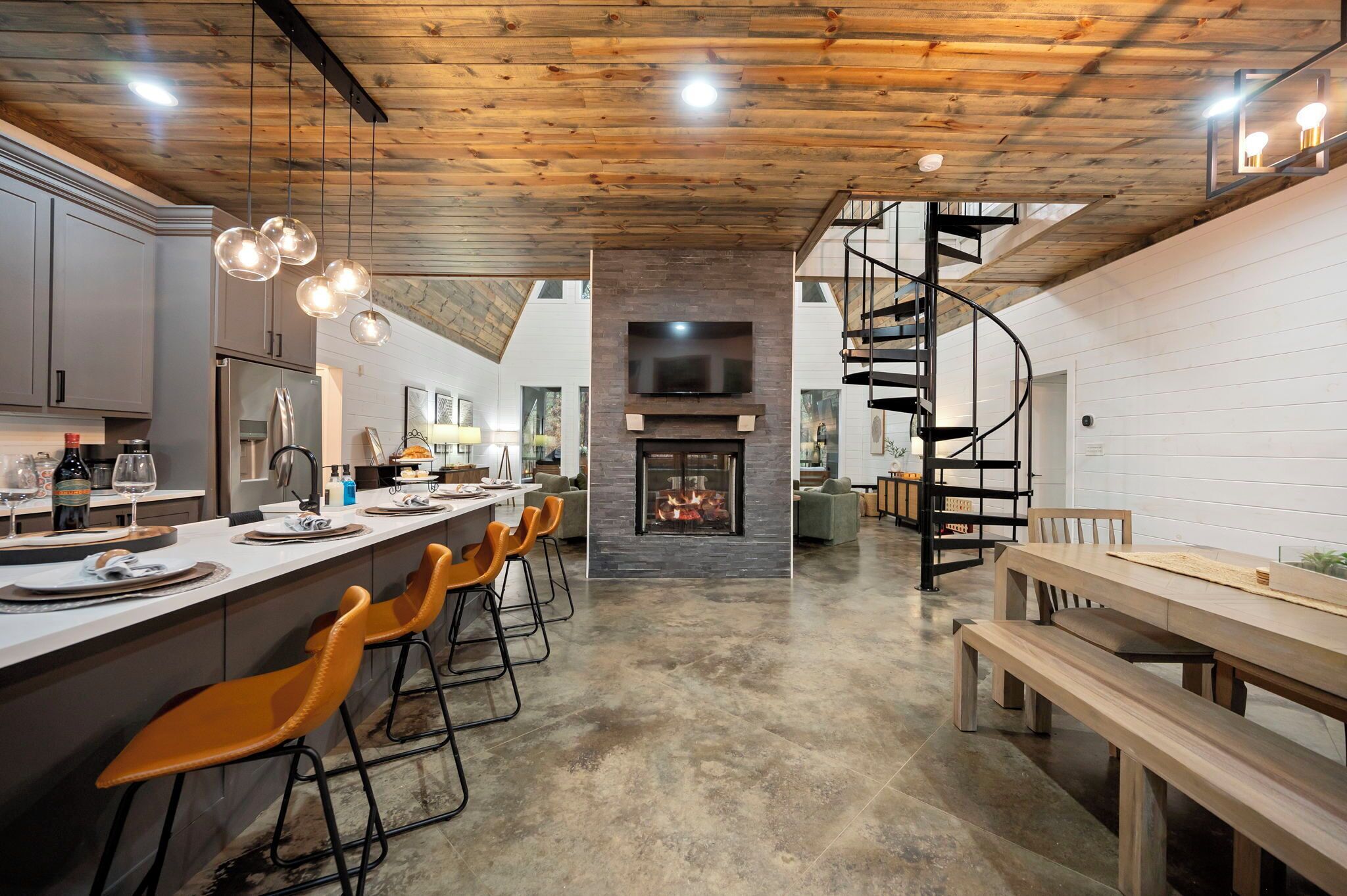 Eine moderne Küche mit Kochinsel, Kamin und Wendeltreppe.