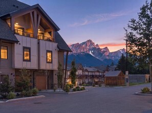 Ein mehrstöckiges Haus mit Balkon, Auffahrt und einem Berg im Hintergrund.