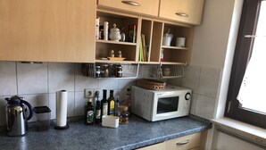Une cuisine dotée de plans de travail en granit, d’armoires en bois, d’un four à micro-ondes et de divers ustensiles de cuisine.