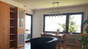 Un salon moderne avec un coin repas, de grandes fenêtres et un placard à portes coulissantes.